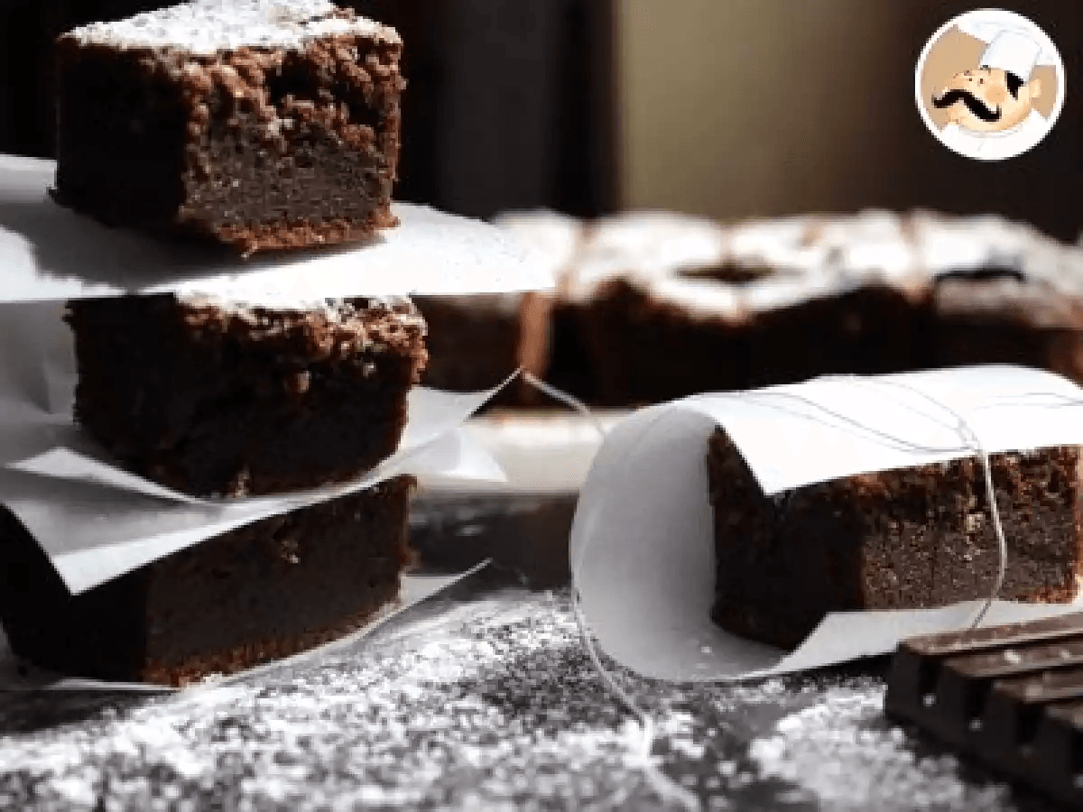 Bánh brownie sô-cô-la cắt vuông, mặt trên nứt nhẹ, ruột mềm ẩm màu nâu sẫm
