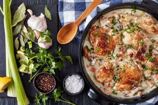Đùi gà om trong sốt kem tươi vàng óng, điểm xuyết nấm và rau mùi tây xanh tươi