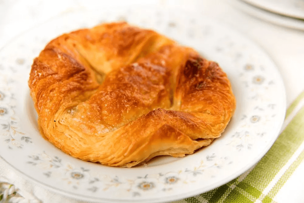 Bánh kouign-amann Bretagne vàng óng, lớp vỏ caramel giòn rụm phủ đường lấp lánh